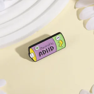 Funny cartoon battery enamel pin with Powered by ADHD text for backpacks and clothing