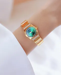 Elegante gouden dameshorloge met groene wijzerplaat en kristallen om de pols detail