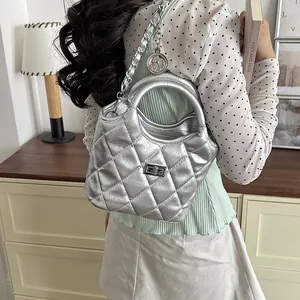 Silver metallic quilted shoulder bag shown on a model in a stylish indoor setting.
