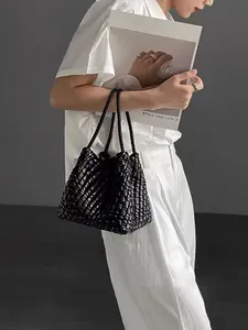 Handcrafted black woven leather bucket bag shown in a stylish lifestyle setting