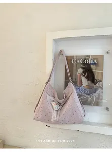 Detail of large lavender polka-dot tote bag with bunny pendant on a wall display