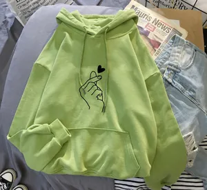 Détail d'un sweat à capuche vert citron avec motif cœur et doublure polaire.