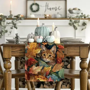 Dettaglio runner da tavola autunnale con gatto tra foglie d'acero in ambiente accogliente.