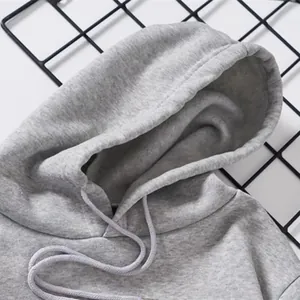 Gros plan sur le détail d'un sweat à capuche en polaire gris avec cordons de serrage.