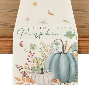 Dettaglio runner da tavola autunnale in lino con stampa a zucca e foglie secche.