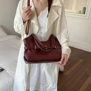 Fashionable dark red leather tote bag styled with a classic beige trench coat for women