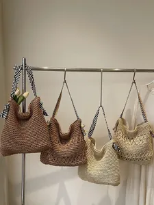 Grands sacs fourre-tout en paille tissée pour femmes en plusieurs couleurs sur un portant