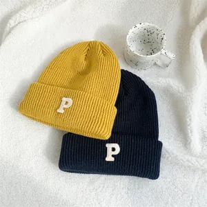 Detailed view of yellow and navy rib-knit beanies with embroidered P letter patch