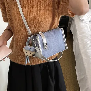 Detailed view of blue denim texture crossbody pillow bag with cute teddy bear charm