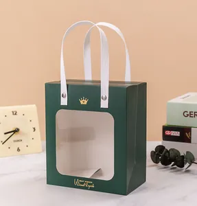 Close-up of a dark green gift bag with a clear window and gold foil crown detail.