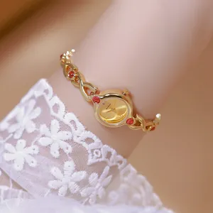 Primer plano de un elegante reloj de pulsera dorado con rubíes sintéticos rojos