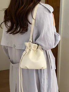 Creamy white drawstring crossbody bag with minimalist litchi grain leather texture.