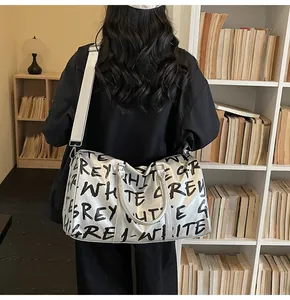 Large silver travel bag with graffiti text carried by a woman in a library setting