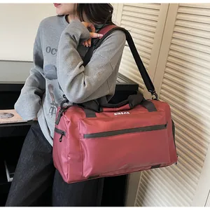 Large burgundy duffel bag for travel and fitness shown on a female model shoulder
