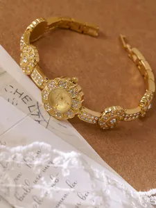 Close-up of vintage gold flower bracelet watch with crystal accents and sunray dial.