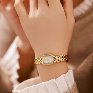Detaillierte Nahaufnahme einer goldenen Vintage-Uhr mit Edelstahlarmband am Handgelenk