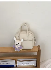 Minimalistische beige quadratische Handtasche mit süßem Hasenanhänger im Holzregal