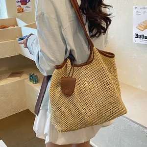 Grande borsa tote in paglia con finiture in pelle portata a spalla in un caffè