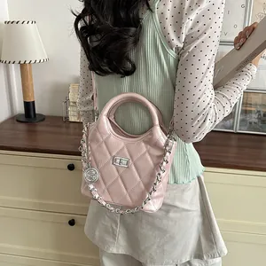 Detailed view of model carrying an elegant pink quilted bucket bag with chain strap