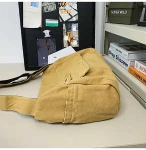 Detailed side view of a minimalist yellow large capacity canvas messenger bag on a desk