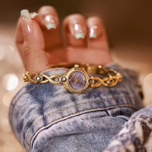 Detalle de reloj vintage dorado con esfera de nácar violeta natural en la muñeca