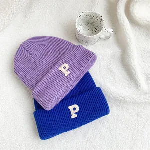 Close-up of two warm knit beanies with embroidered letter P in purple and blue colors