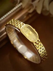 Detalle de reloj retro ovalado de acero dorado con elegante correa de eslabones