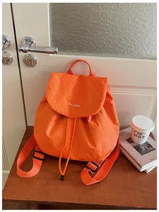 Minimalist lightweight orange grid backpack for women shown on a wooden desk.