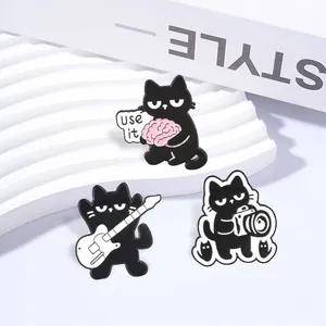 Detailed view of three cute black cat enamel pins with guitar, camera, and brain motifs.