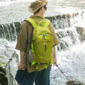 Randonneur avec un sac à dos de randonnée vert lime respirant près d'une cascade d'eau