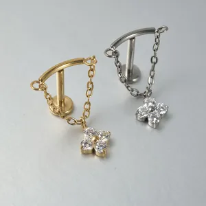 Close-up of G23 titanium labret studs with dangling chains and cubic zirconia flowers.