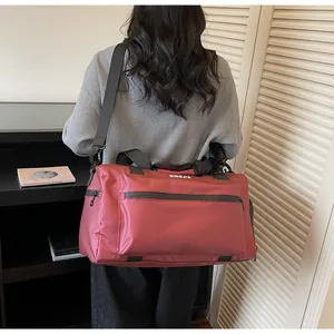 Detailed back view of a large burgundy travel bag showing shoulder strap and carry handles.