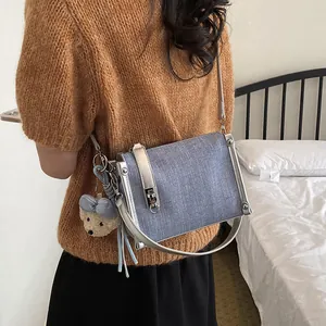 Light blue textured crossbody pillow bag with cute bear charm and adjustable silver strap