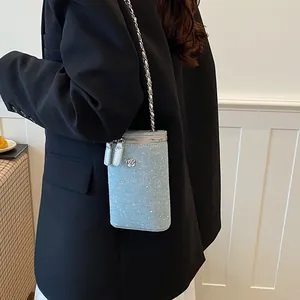 Detail of light blue denim crossbody phone bag with rhinestones and chain strap on black blazer