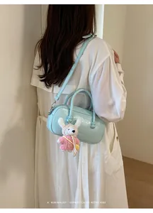 Détail de sac bowling en cuir bleu clair avec bandoulière et mignon pendentif lapin en tricot.