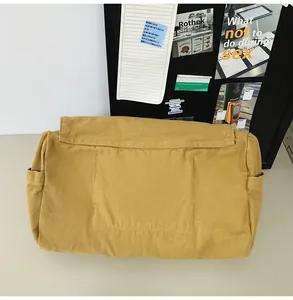 Close-up of a mustard yellow canvas messenger bag showing back pocket detail