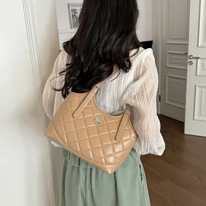 Rückansicht einer Frau mit einer khakifarbenen gesteppten Schultertasche am Arm