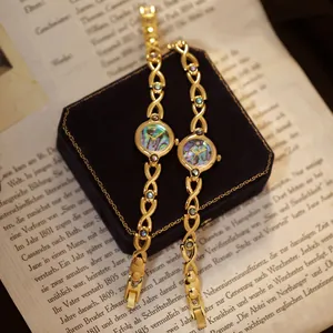 Relojes de pulsera dorados con esfera de concha de abulón sobre un libro antiguo