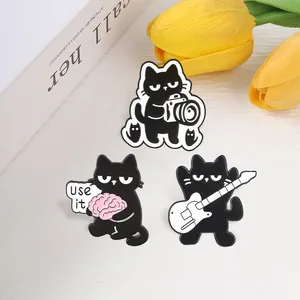 Detailed view of three cartoon black cat enamel pins with camera, brain, and guitar