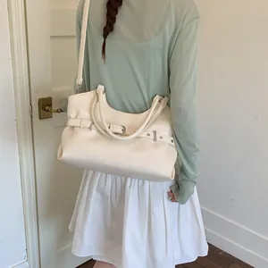 Elegant cream white faux leather tote bag shown as an underarm shoulder bag on a model