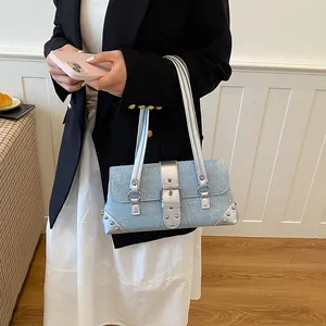 Woman wearing a sparkling blue baguette armpit bag with silver buckles and studs