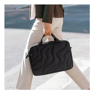Close-up detail of a woman carrying a black puffy quilted laptop bag in a street scene