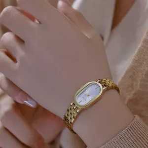 Elegante reloj vintage ovalado dorado para mujer con correa de acero en la muñeca