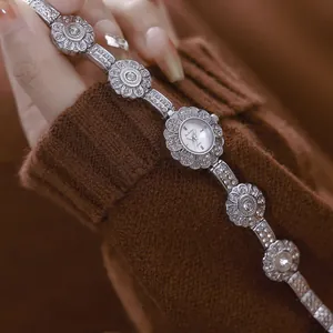 Close-up detail of a vintage flower bracelet watch with rhinestones on a brown knit sleeve