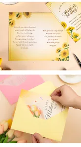 Close-up of Mother's Day greeting card with floral design being put into a yellow envelope.