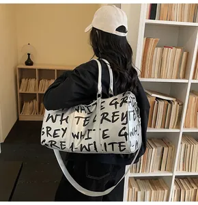 Large silver gym bag with black graffiti print carried in a stylish modern library.