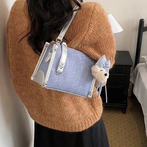 Back view of a chic denim blue crossbody bag with a cute bear charm on a model.