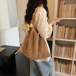 Borsa a tracolla grande in rete intrecciata stile boho con accenti floreali su modella.
