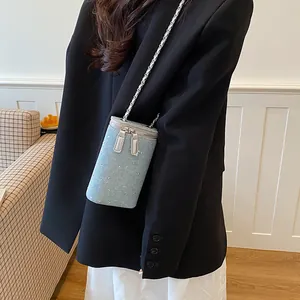Detailed view of a light blue denim crossbody bag with rhinestones and chain strap