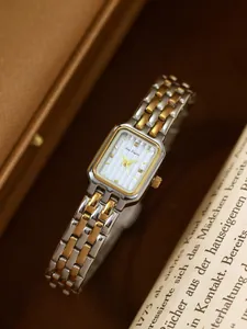 Elegante zweifarbige Bee Sister Rechteckuhr auf Vintage-Buch und Lederetui Hintergrund